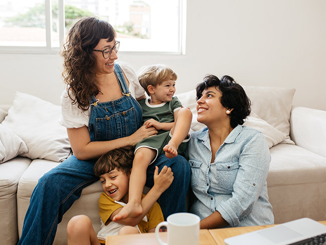 2 women with their 2 small children playing inside their home
