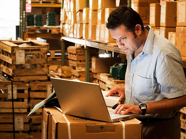 man inside warehouse working on laptop