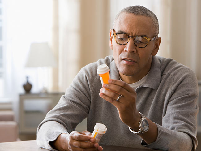A man looking at pharmacy bottle.