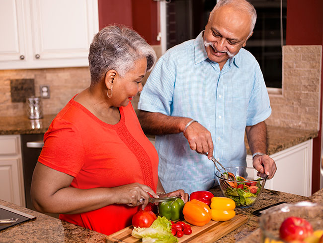 Happy senior adult couple cooking together in home kitchen