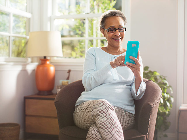 Woman sitting in armchair and using her mobile phone