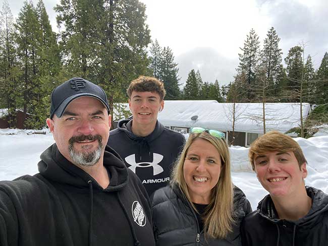 Mariann Stephens, her husband and two sons smiling at the camera while taking a selfie on a snowy day.