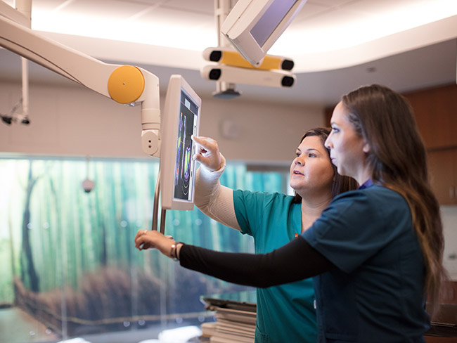 2 women medical technicians examining a digital imaging scan