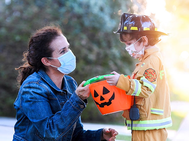 older woman and a young boy wearing protective face masks before going trick-or-treating