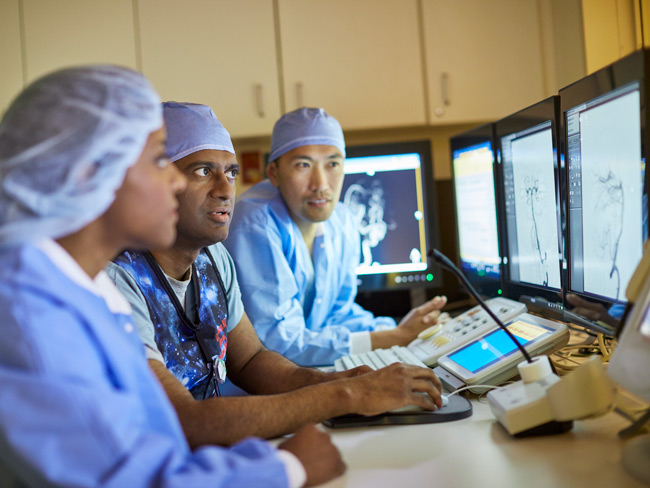 medical employees wearing scrubs viewing digital monitors