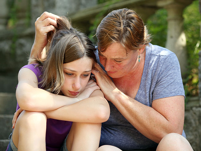 mother consoling despondent daughter 