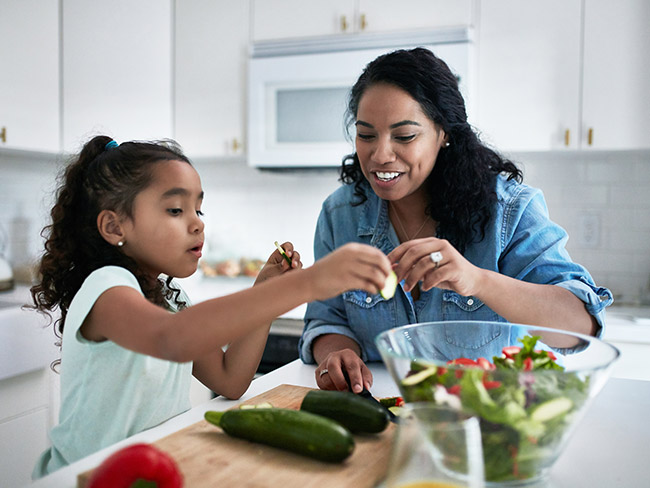 Mother and daughter making salad together in a kitchen