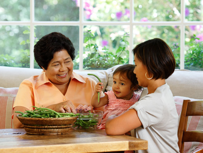 Grandmother, mother and granddaughter at a table stringing green beans