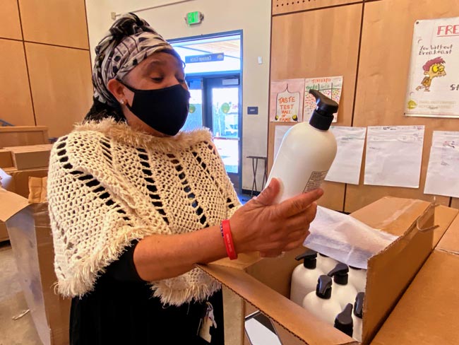 Natasha Moore wearing a protective facemask looking at a bottle of sanitizer.