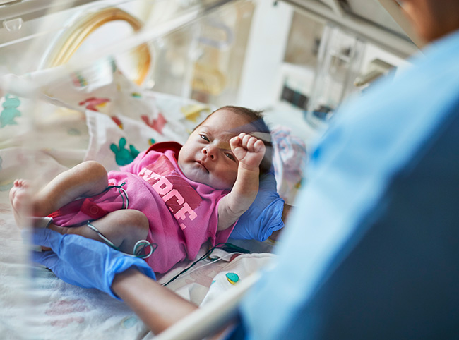 Newborn baby in a hospital incubator.