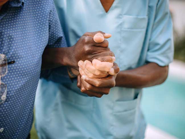 A nurse clasping the hand's of a patient. 