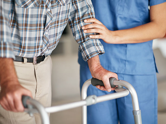 A nurse assisting a man who's using a walker for support