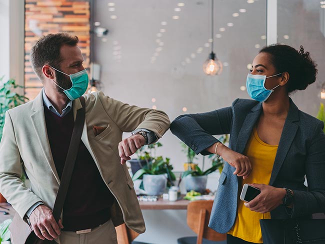 Colleagues in the office practicing alternative greeting to avoid handshakes during COVID-19 pandemic