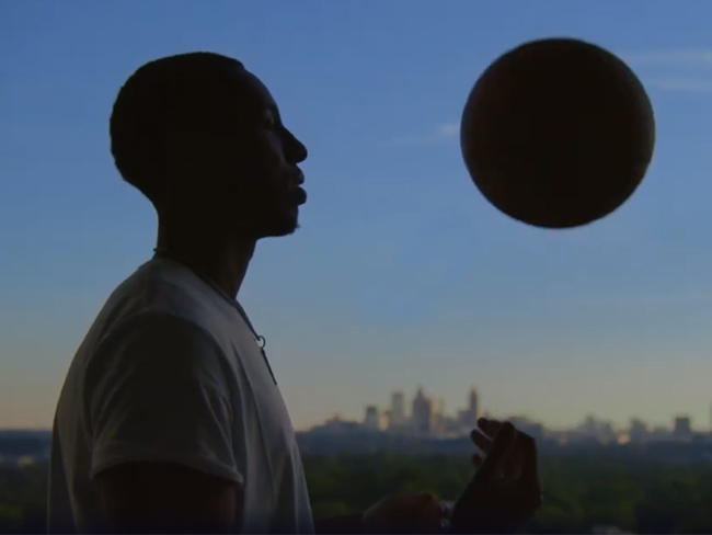 silhouette of man and basketball against a background of city skyline and dim sky