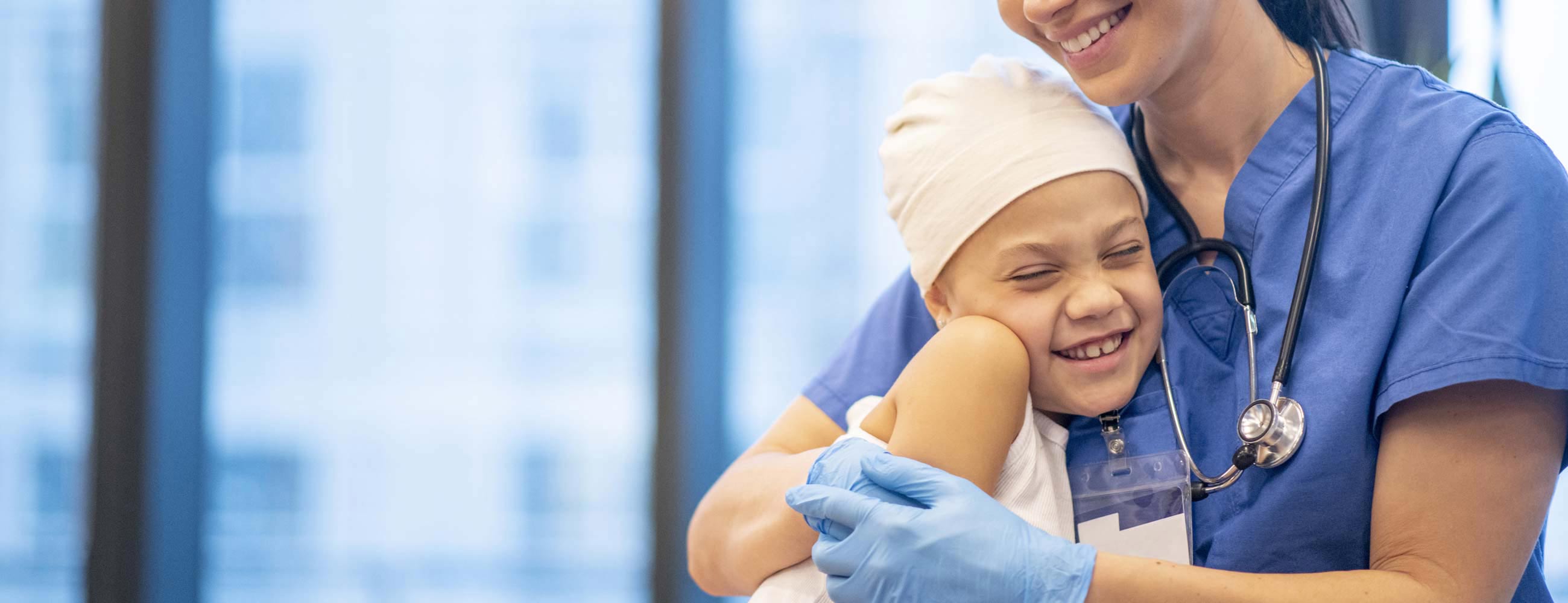 A smiling young cancer patient being hugging her physician.