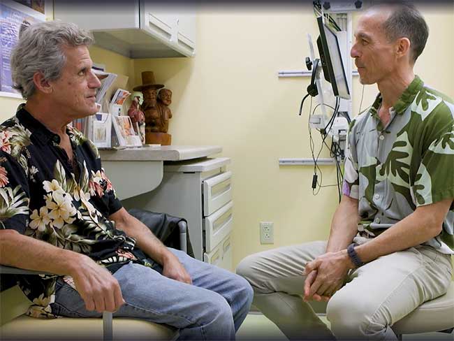 Paul Lance sitting across from Tarquin Collis, MD during a medical exam.