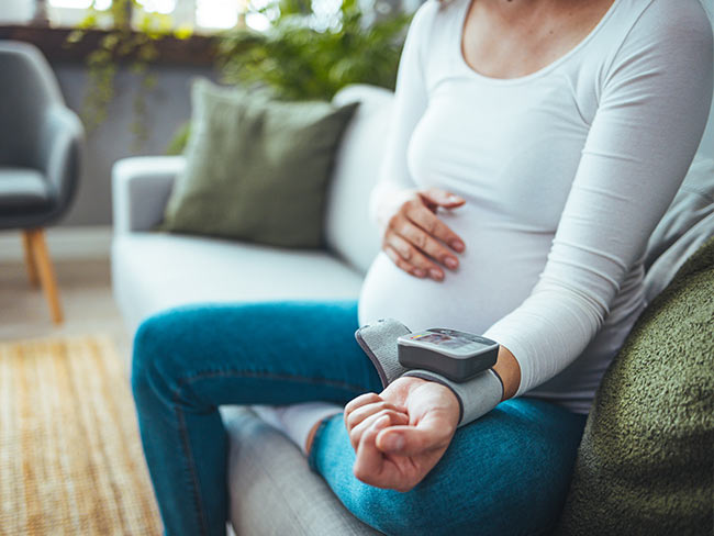 Pregnant woman checking blood pressure at home