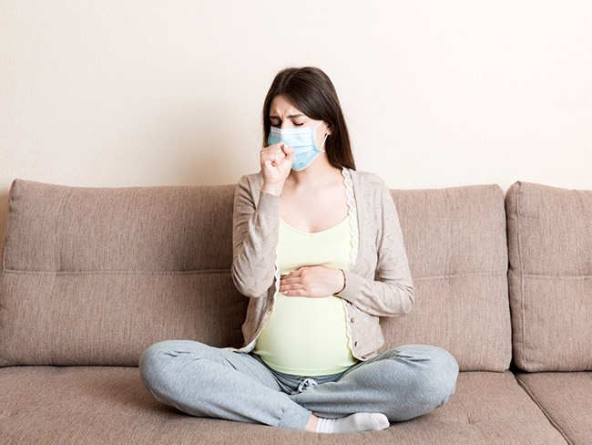 Pregnant woman coughing in mask