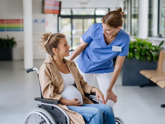 pregnant woman in wheelchair speaking with nurse