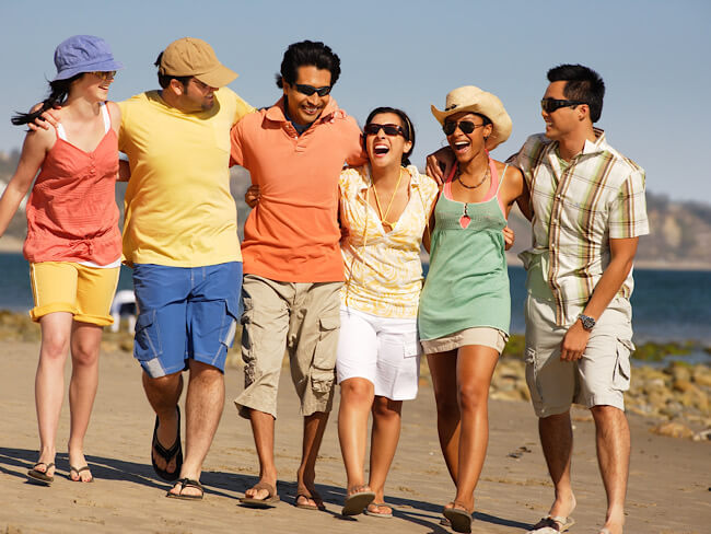 A group of people walking on the beach with their arms around each other's shoulders. 