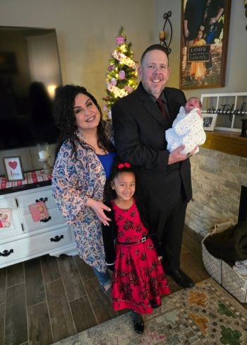 Cardosi family standing in living room with new baby