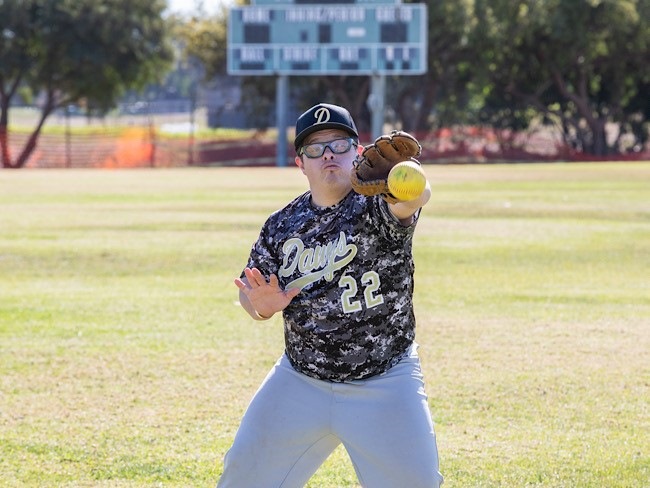 A Special Olympics athlete holds his glove out to catch a softball.