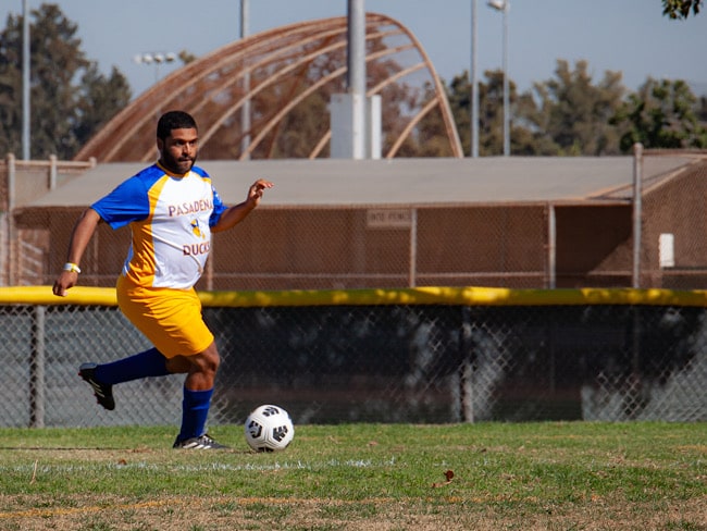 An athlete kicks a ball across a soccer field.