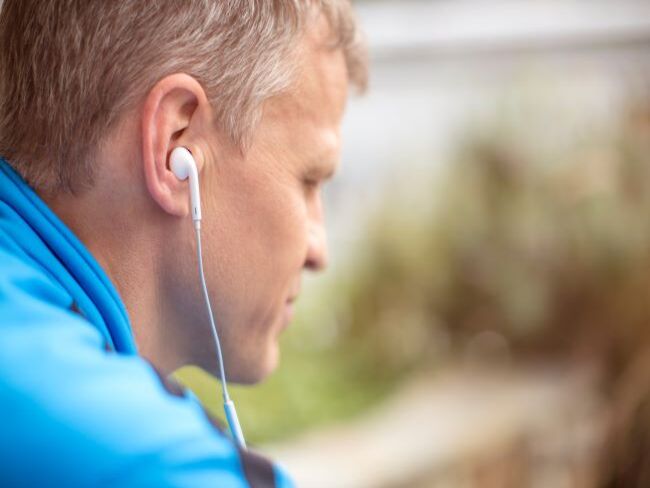 Man outside wearing earbuds listening to an app