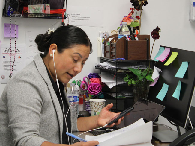 woman seated at office desk speaking on a phone