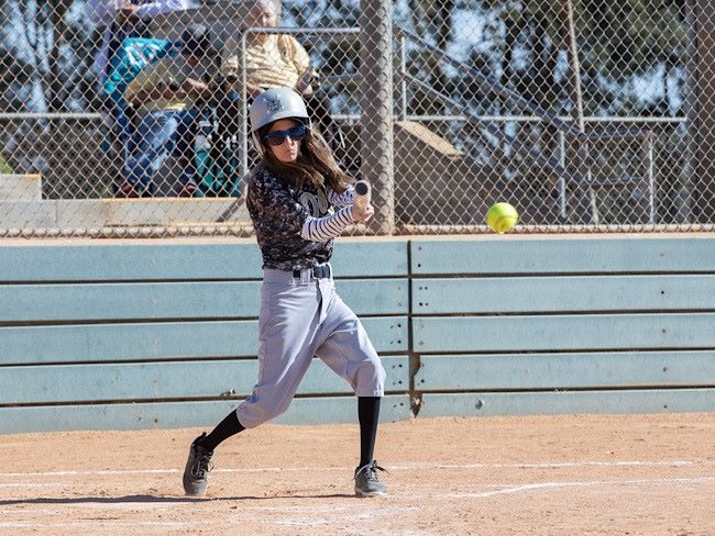 A Special Olympics athlete swings her bat at a softball.