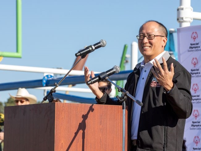 Dr. Nolan Chang speaks in front of a lectern, smiling and gesturing broadly.