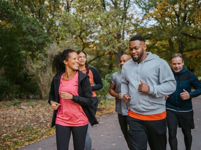 A group of people smiling and jogging outside together.
