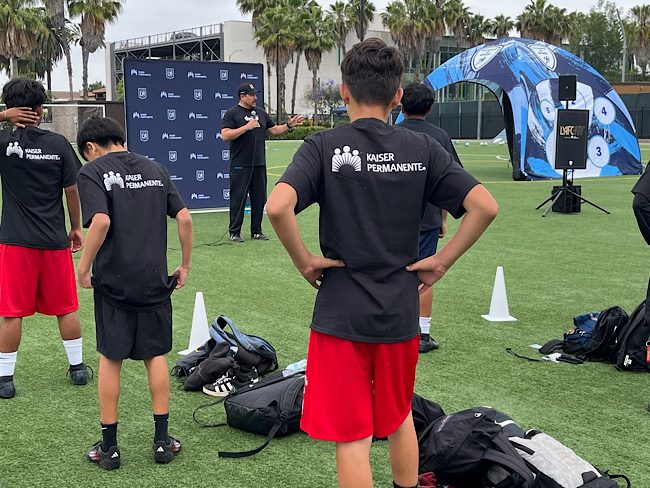 Robert Fernandez is leading a group of teenagers in an energizing stretch in a park
