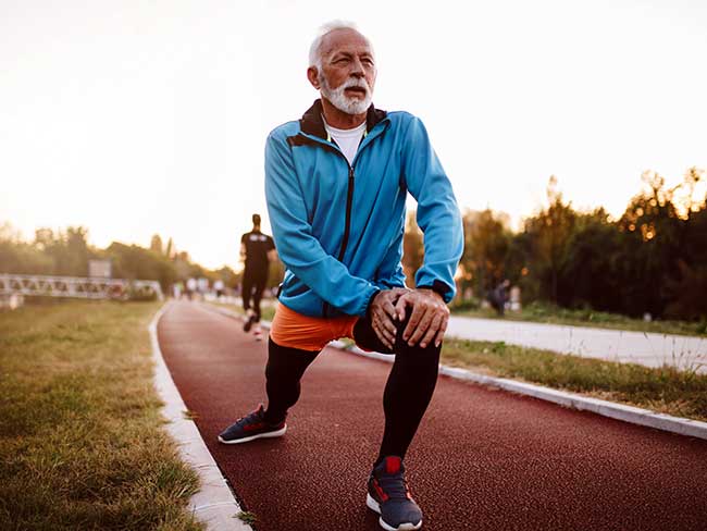 Senior man stretching before jogging on a running track