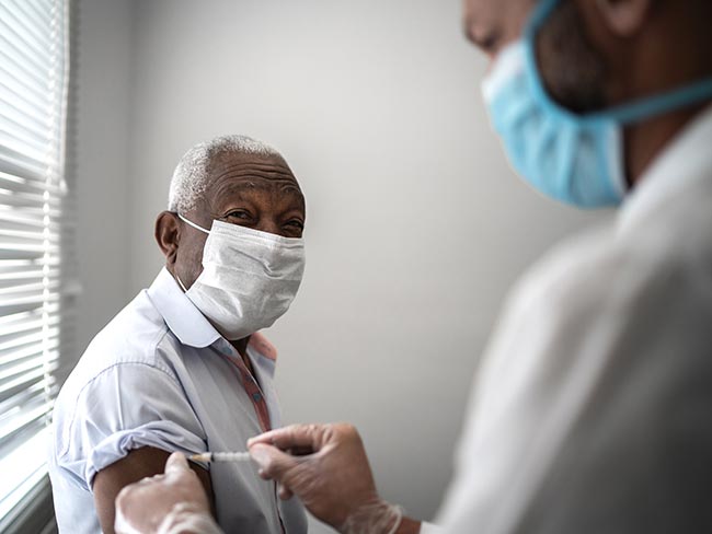 A senior man in a protective face mask getting his COVID-19 vaccination.
