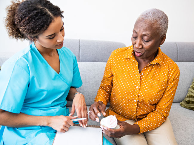 nurse seated with senior woman discussing her prescription medication