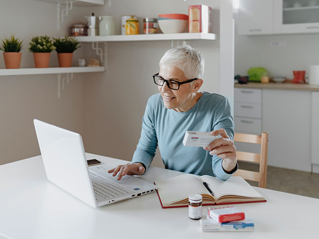 Senior woman looking up information about medication online using laptop. 
