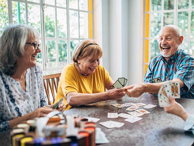Group of seniors laughing during a game of cards.