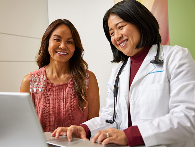 Doctor typing notes in a computer while smiling with her patient