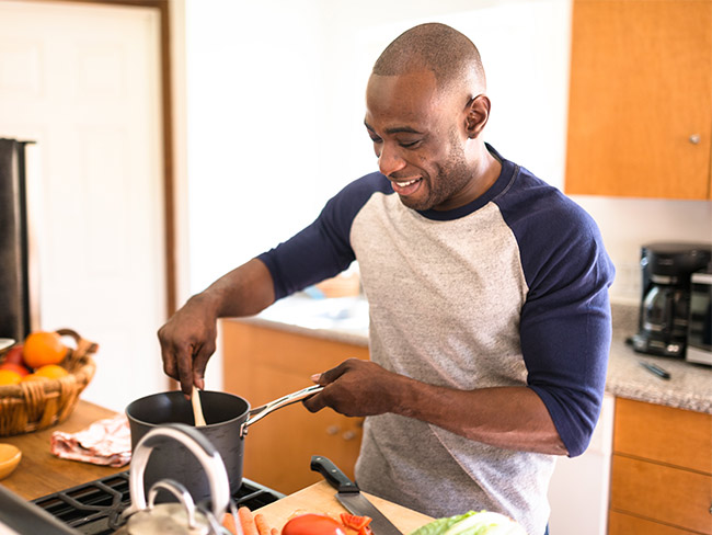 Smiling Black man cooking.