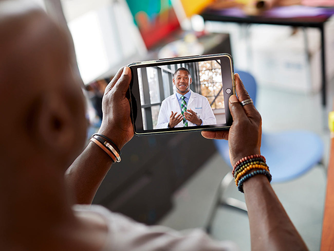 man holding tablet computer for a video call with his doctor