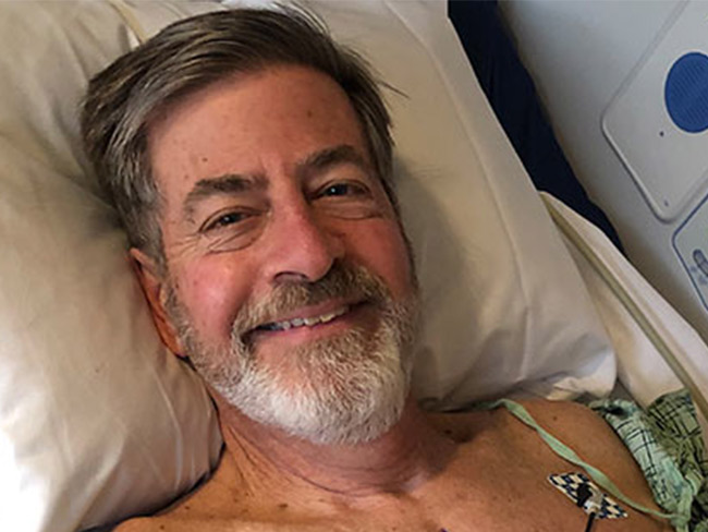 smiling man lying on hospital bed