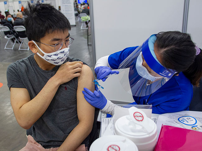Daniel Jing gets a COVID-19 vaccination at the large, temporary vaccination site at the Moscone Center in San Francisco.