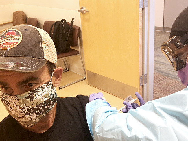man wearing face mask receiving vaccine injection