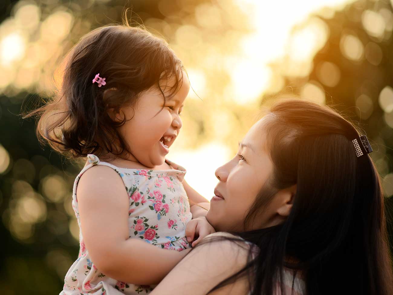 A young Asian mother hugging her laughing toddler girl. 