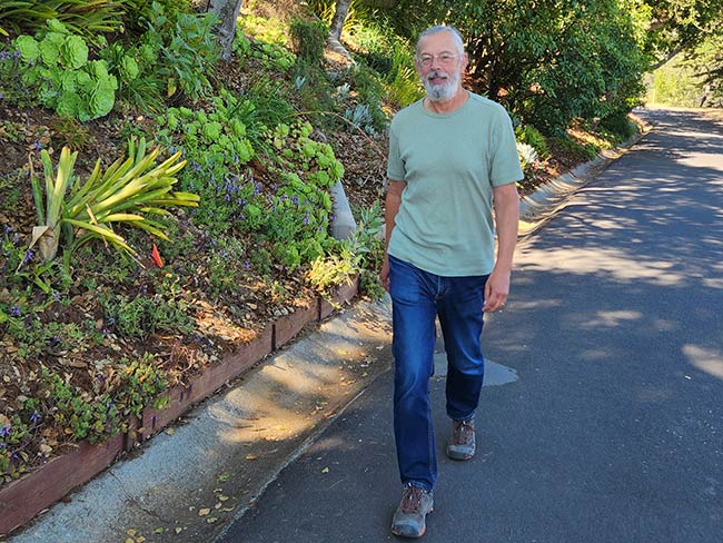 Stephen Van Den Eeden walks outside near lots of trees and bushes  