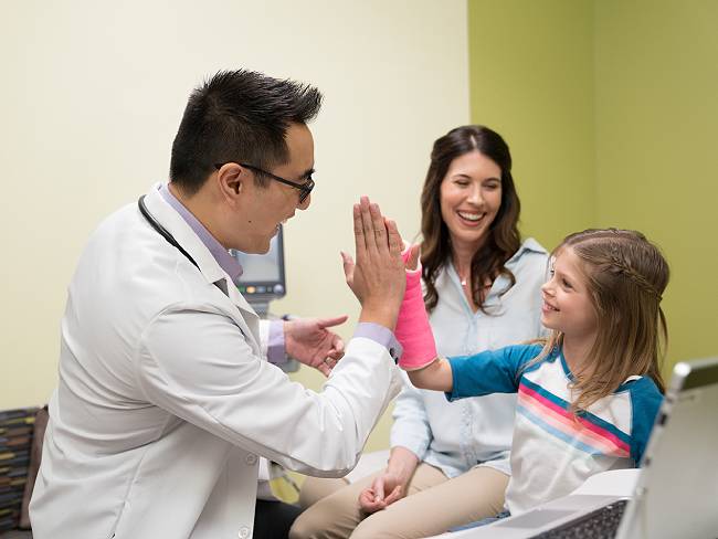 Doctor gives girl with arm cast a high five
