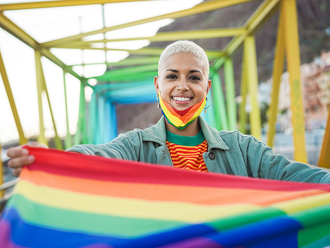 Young gay woman holding lgbt rainbow flag