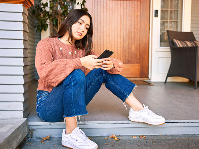 Woman sitting on porch steps with phone