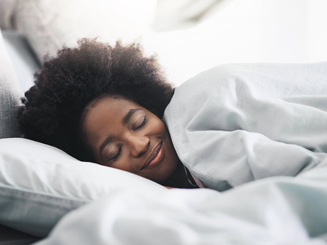 Woman sleeping peacefully under white sheets